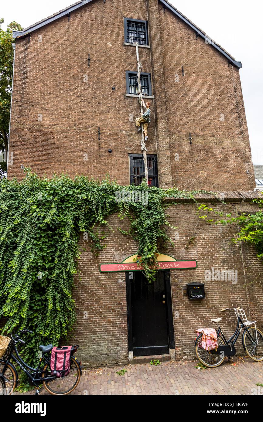 Una figura si arrampica fuori da una finestra con sbarre su una corda di stoffa al Charles Dickens Kabinet nel Bergkwartier, il quartiere storico della vecchia città di Deventer, una delle nove città anseatiche storiche sull'IJssel, provincia di Overijssel, Paesi Bassi. Il piccolo museo Dickens occupa un'ex prigione femminile su Walstraat, ancora riconoscibile dalle sue finestre con sbarre. Foto Stock