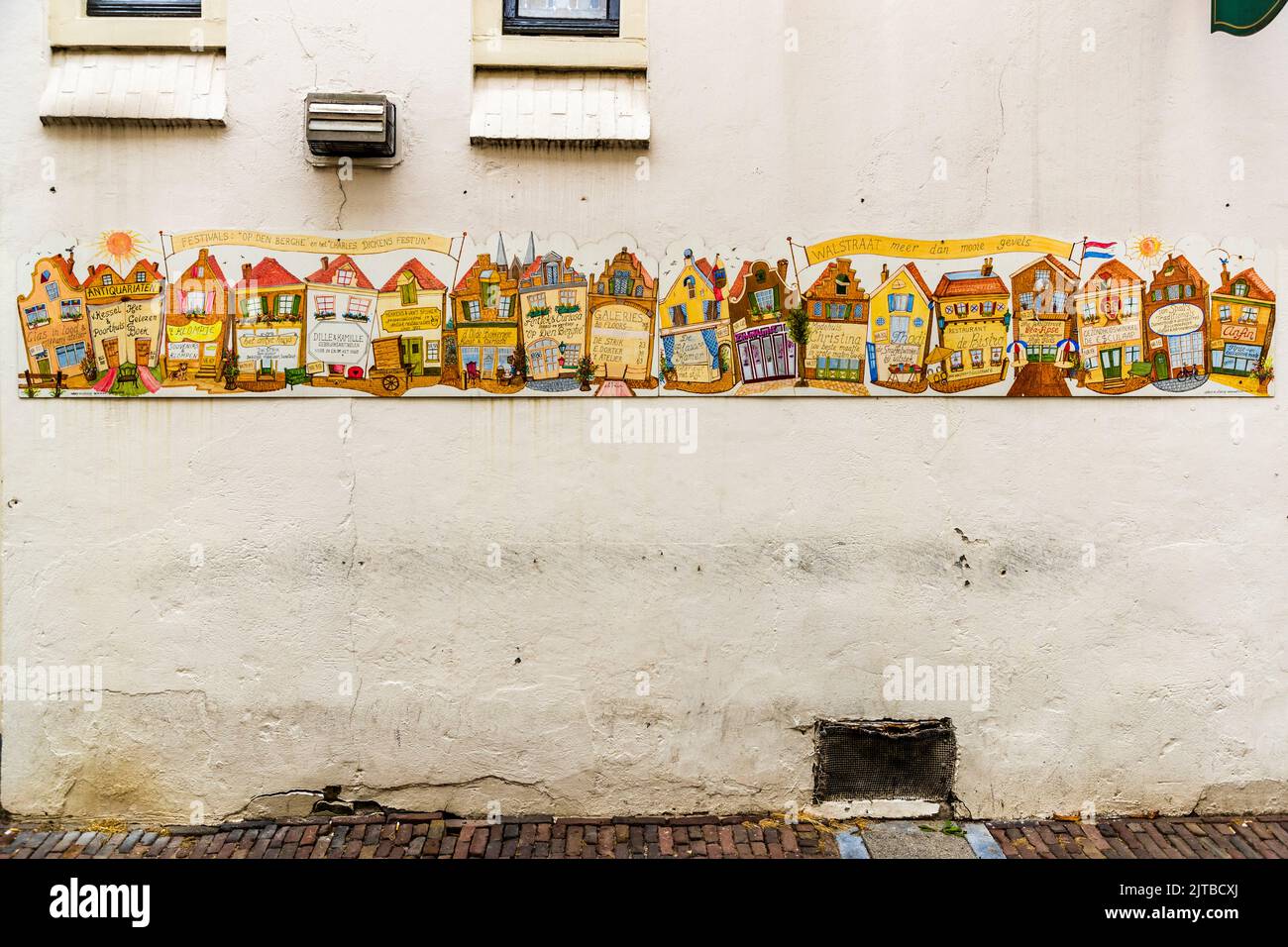 Un murale colorato nel Bergkwartier, il quartiere storico della vecchia città di Deventer, una delle nove città anseatiche storiche sull'IJssel, provincia di Overijssel, Paesi Bassi, raffigura una fila delle facciate tipiche delle case del quartiere in miniatura, ognuna con il proprio frontone e forme di finestre individuali. Uno striscione giallo sopra reca un'iscrizione olandese che si riferisce a una festa di strada. Foto Stock