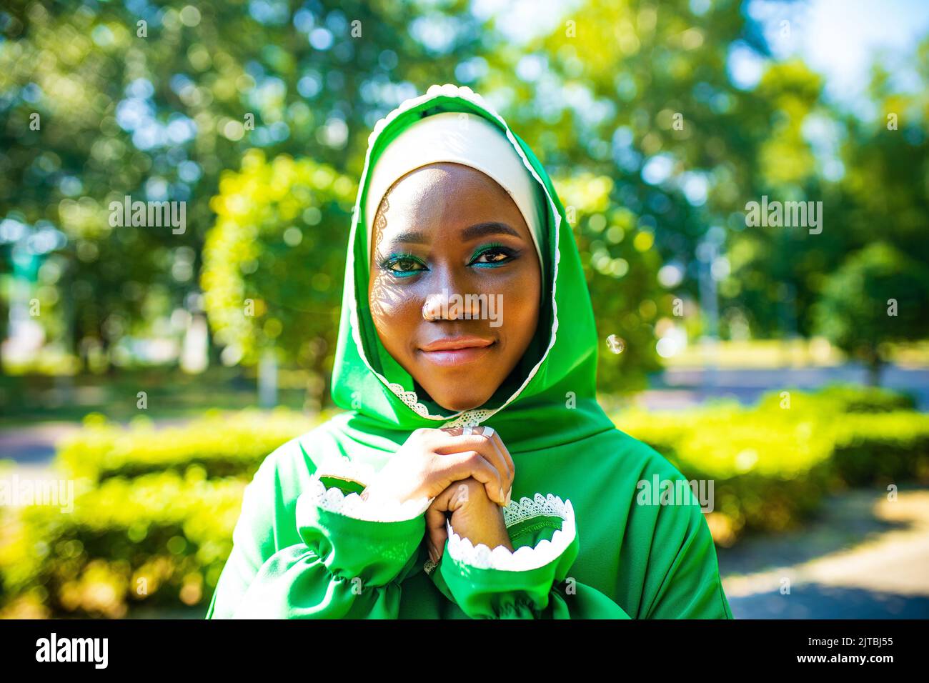 Ritratto di una bella sposa musulmana latino ispanica con make up in abito da sposa verde nel parco estivo Foto Stock