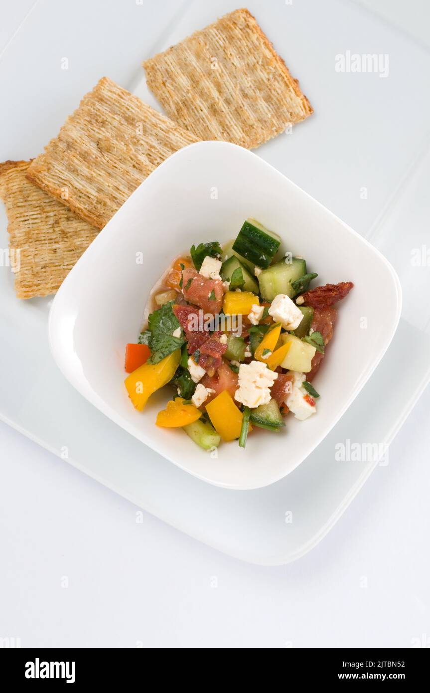 Bella insalata fresca con formaggio Feta e cracker su sfondo bianco verticale Foto Stock