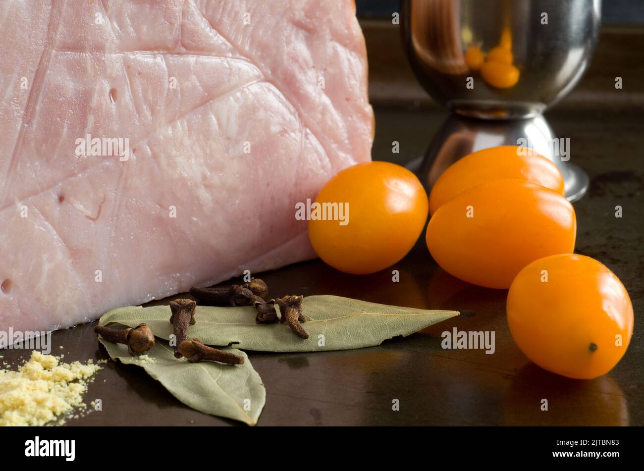 Prosciutto delizioso con pomodori, chiodo di garofano, senape secca e foglie di baia orizzontali Foto Stock