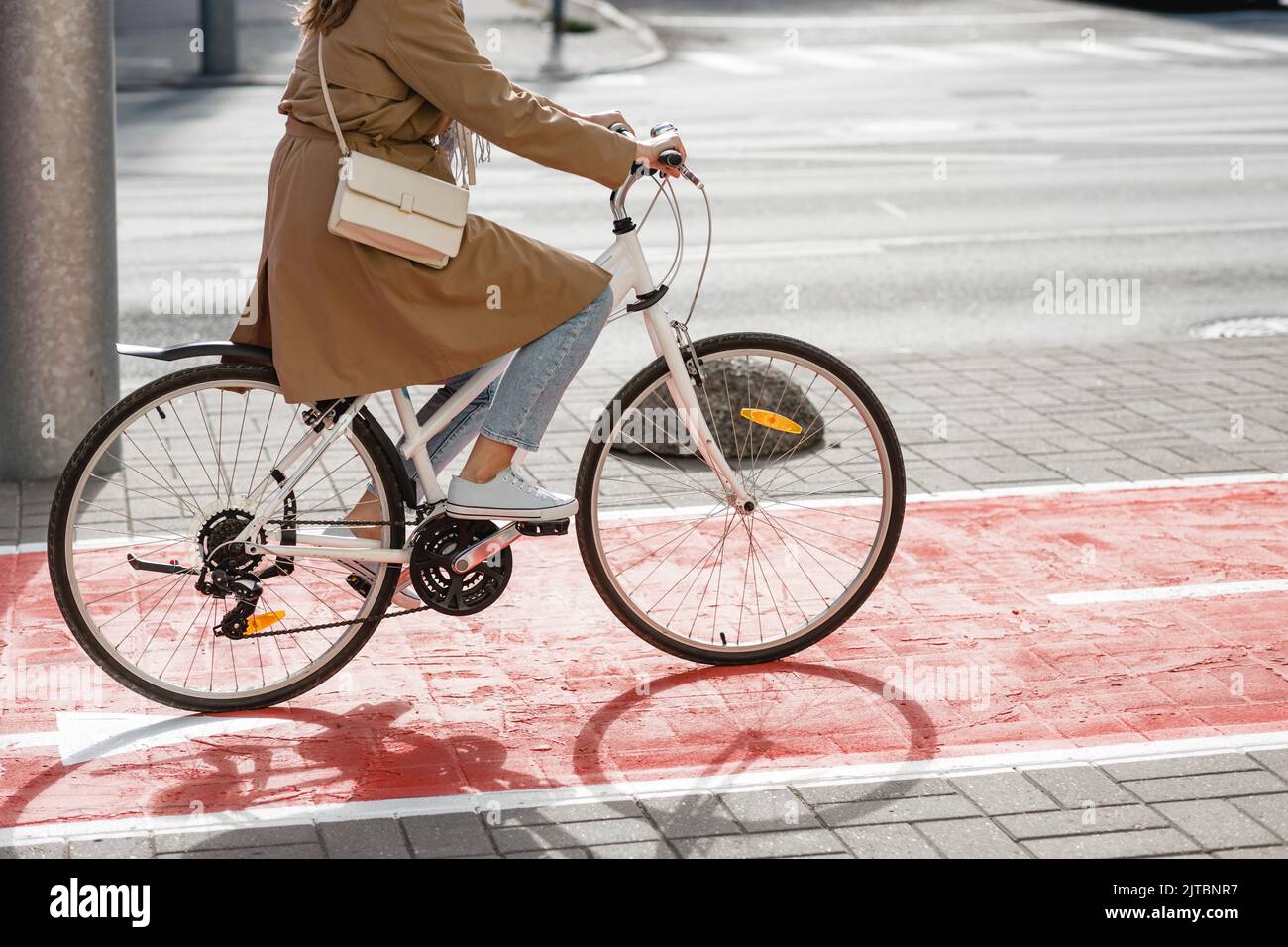 donna in bicicletta lungo la pista ciclabile rossa in città Foto Stock