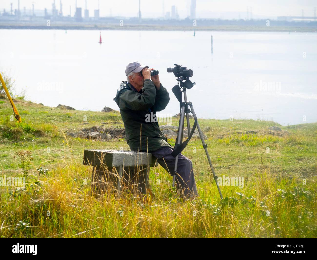 Un anziano birdwatcher maschio che guarda attraverso binocoli e un campo di avvistamento a Teesmouth Redcar Foto Stock