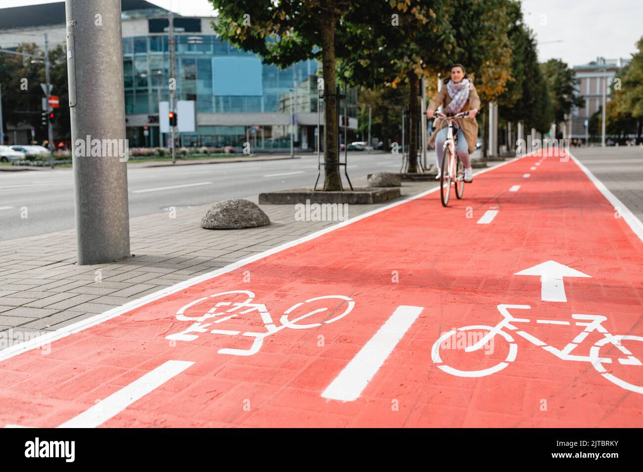 donna in bicicletta lungo la pista ciclabile rossa in città Foto Stock