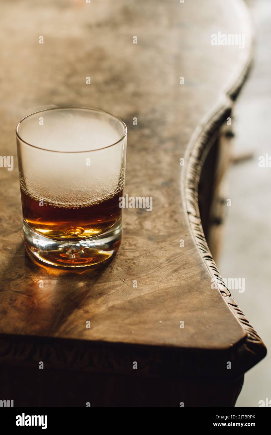 Bicchiere di whiskey con ghiaccio secco, fumo su credenza di burl wood Foto Stock