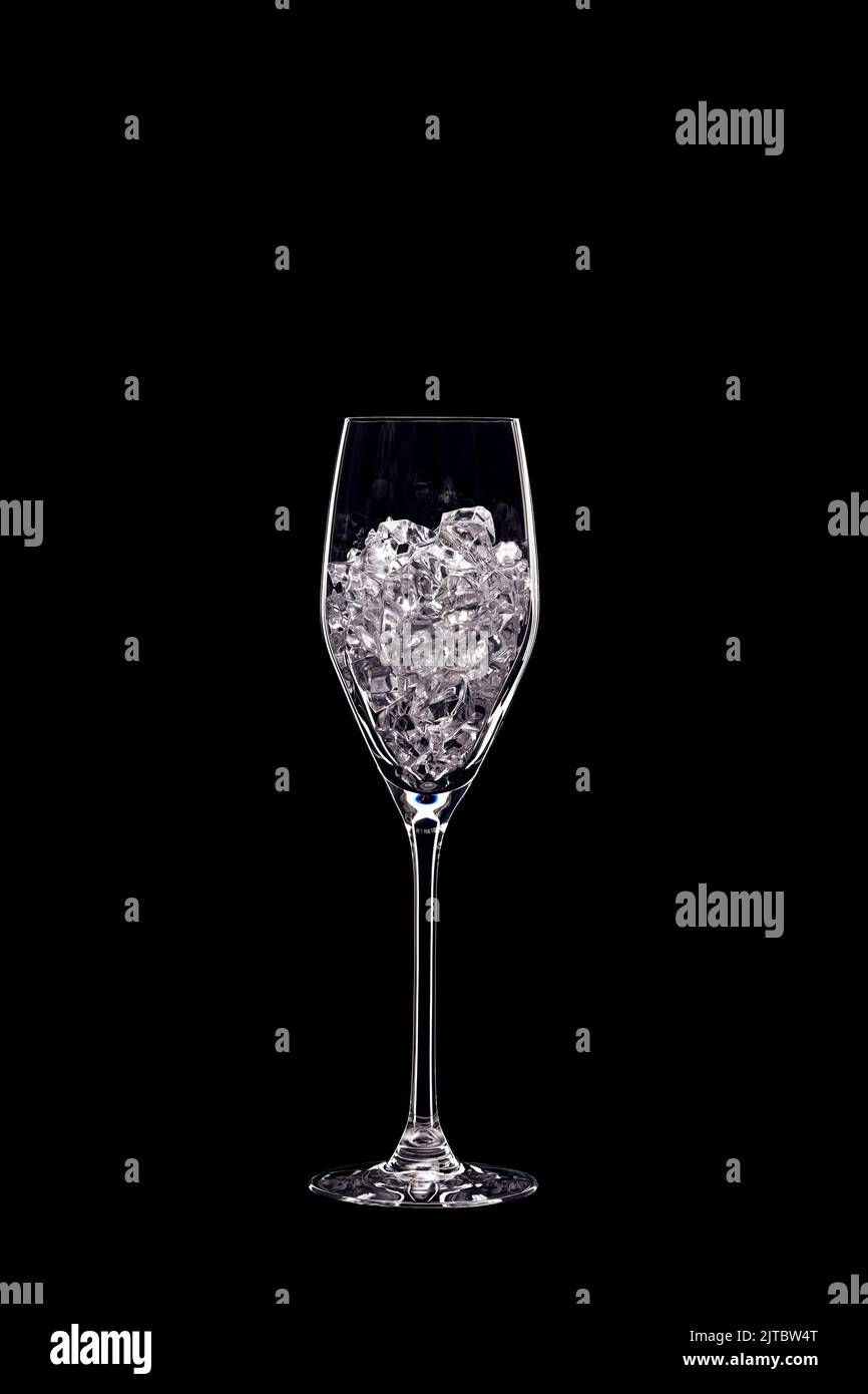 Flauto di Champagne piena di cristalli trasparenti retroilluminati e isolata su sfondo nero. Concetto di vetreria per bevande. Spazio di copia. Foto Stock