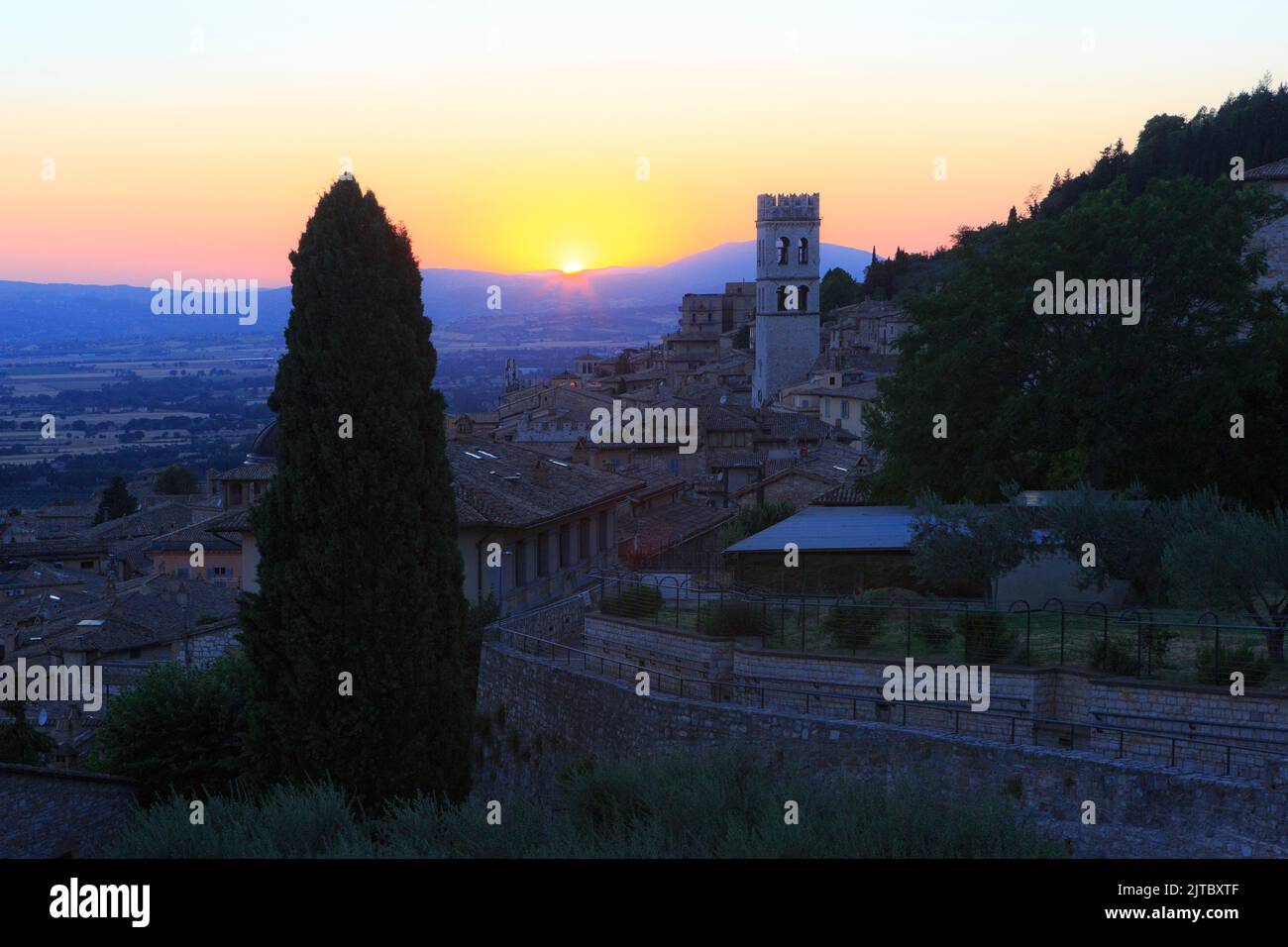 Tramonto sulla medievale Torre del Popolo e altri interessanti edifici e chiese di Assisi (provincia di Perugia), Umbria, Italia Foto Stock