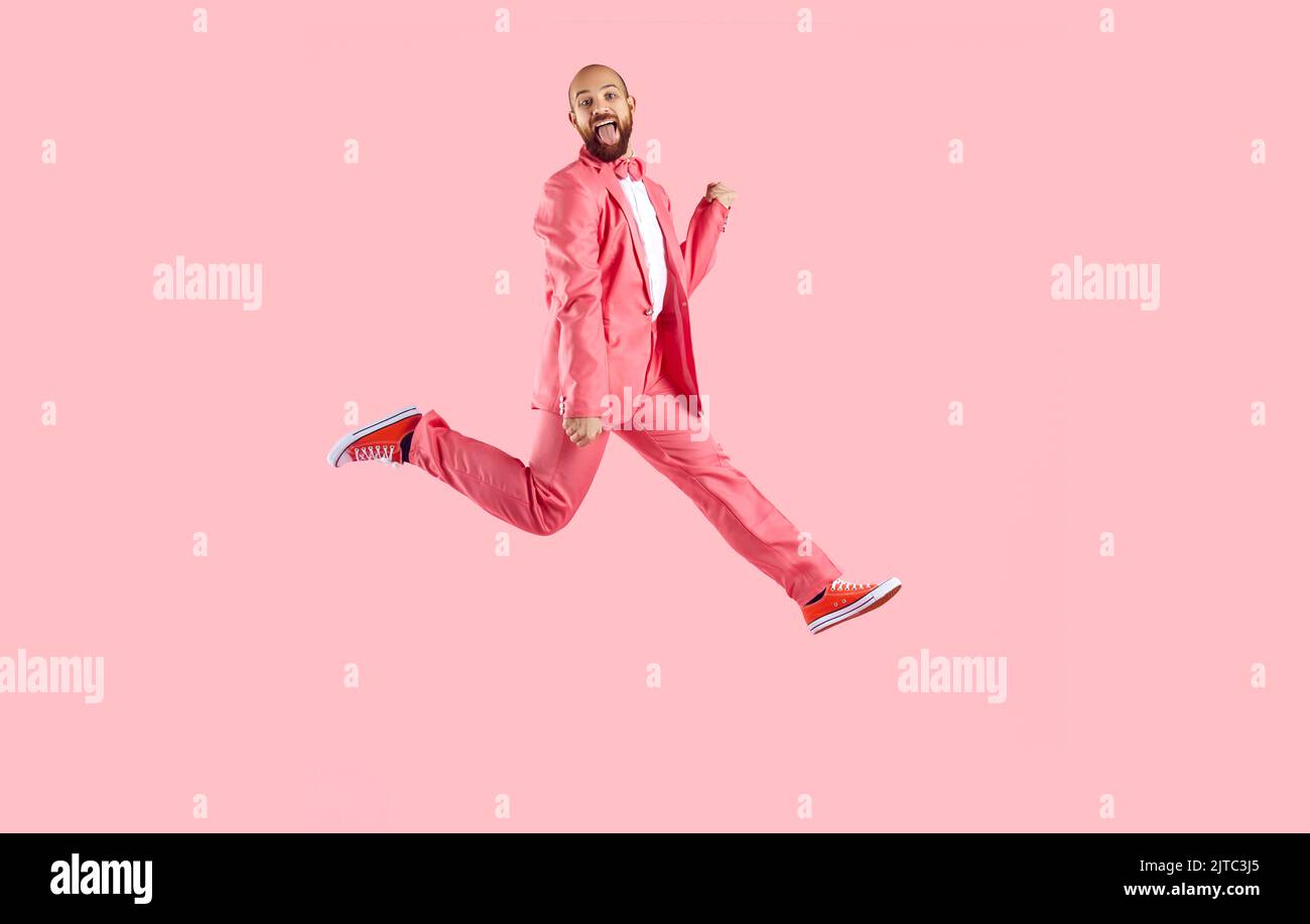 Un uomo con grande gioia che interprete in tuta dance su sfondo rosa Foto Stock