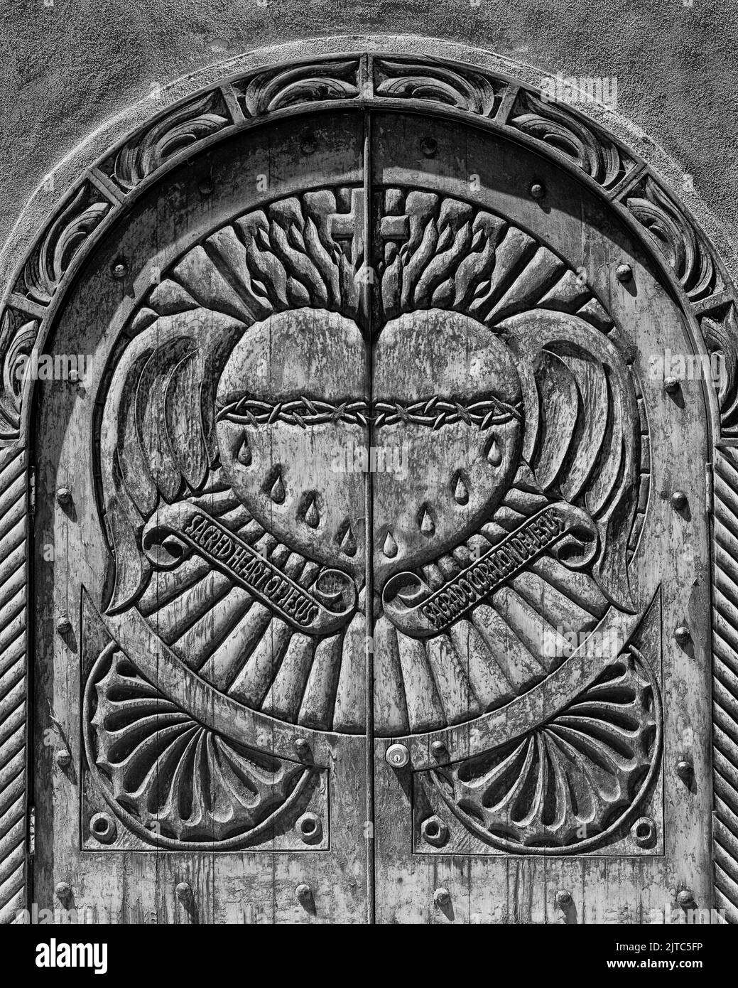 Il sacro cuore di Gesù incisa in una porta di legno della Chiesa cattolica del Sanctuario de Chimayo a Chimayo, New Mexico Foto Stock