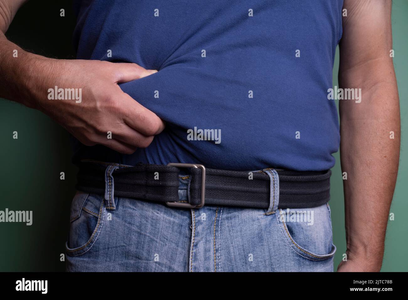 un uomo che tocca il ventre per misurare lo strato di grasso nel suo corpo. Foto Stock
