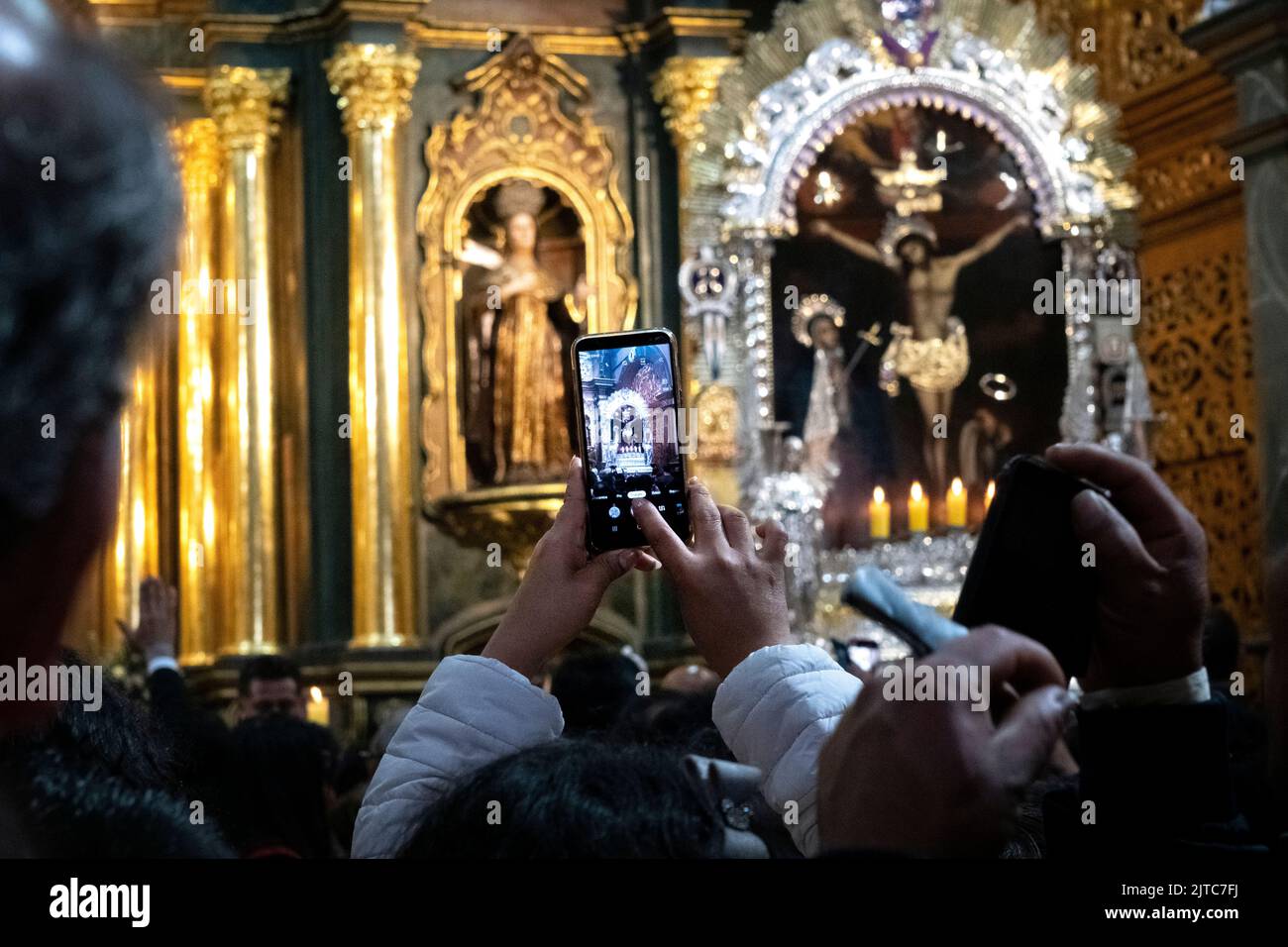 I devoti scattano foto dell'altare maggiore e dell'immagine processionale con i loro telefoni cellulari nella chiesa di Las Nazarenas - Signore dei Miracoli. Foto Stock