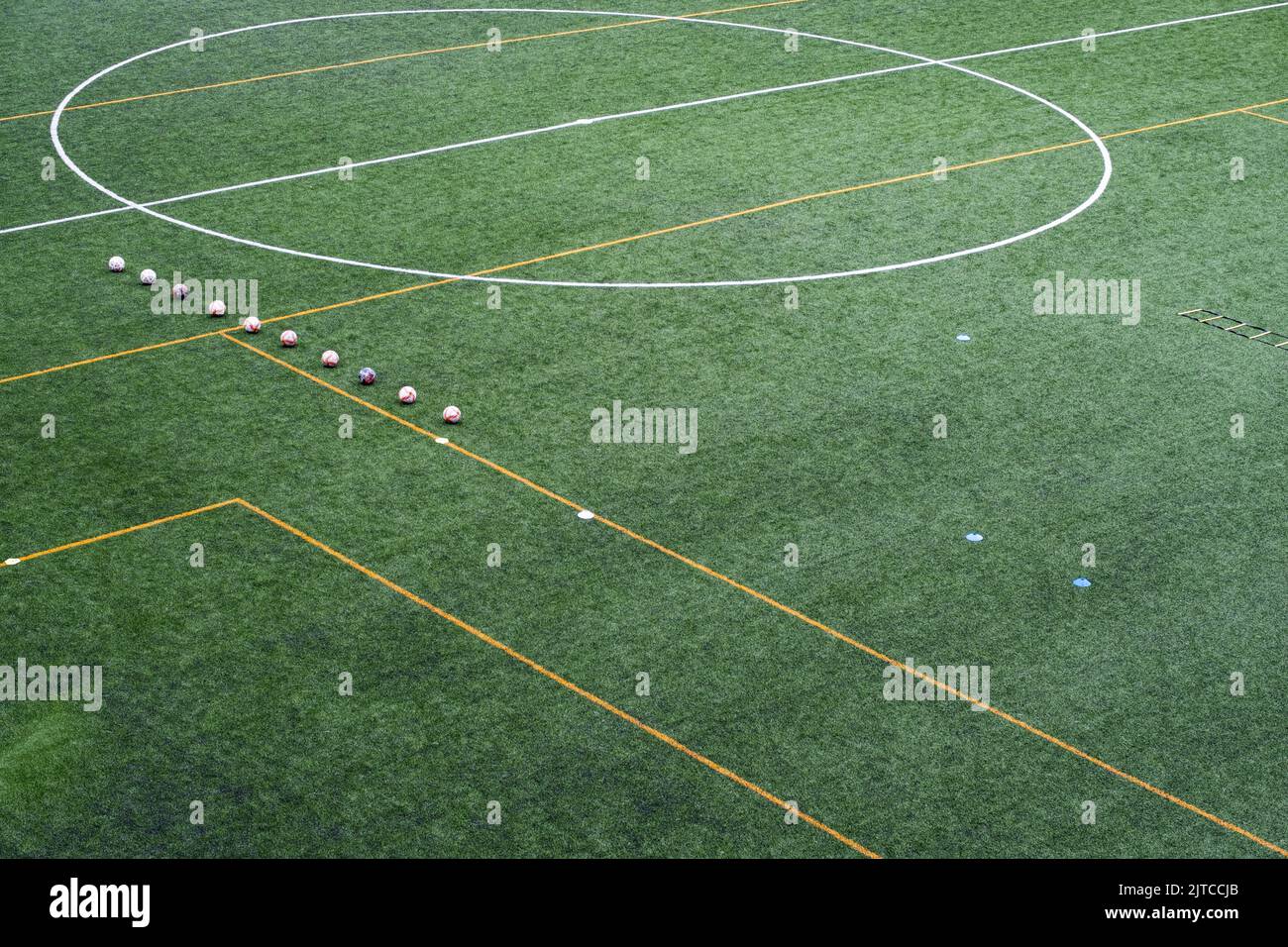 Palle da calcio allineate sul campo prima della sessione di allenamento della squadra locale. Attrezzatura per la sessione di allenamento sulla superficie di un tappeto erboso artificiale. Foto Stock