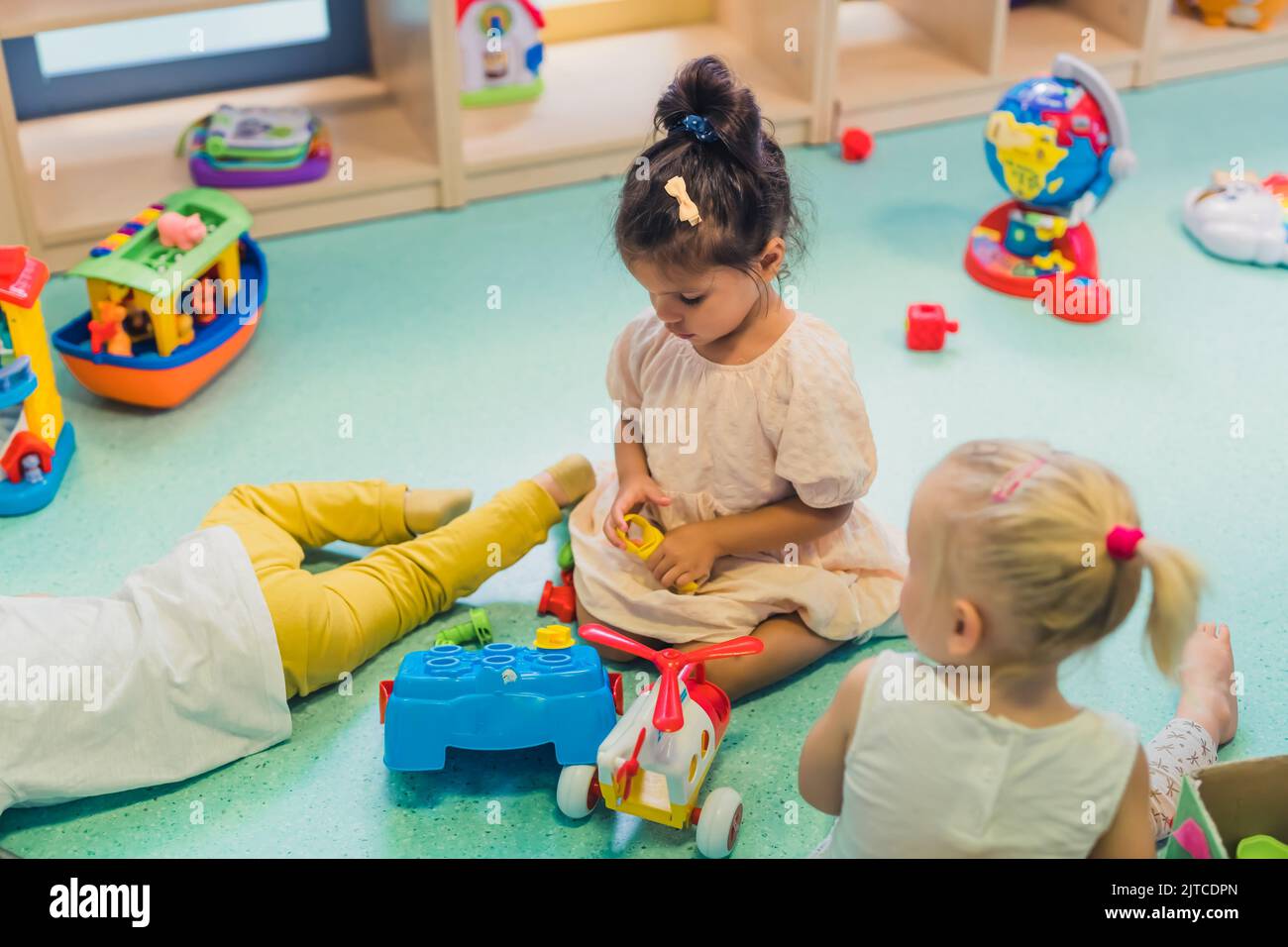 I bambini che giocano con un giocattolo selezionatore di forma plastica, un elicottero colorato, barche e altri giocattoli. Lavora sulle capacità di problem-solving, sullo sviluppo delle capacità motorie e motorie grossolane attraverso il gioco sensoriale nella scuola materna. Foto di alta qualità Foto Stock