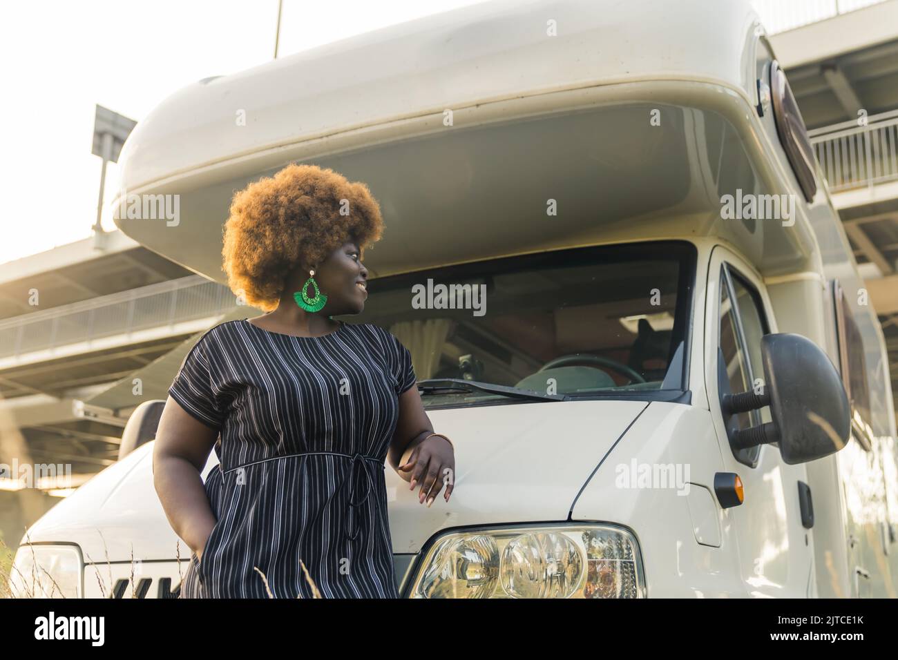 Scatto medio di una donna afro-americana in piedi davanti al furgone, all'aperto estate e concetto di viaggio. Foto di alta qualità Foto Stock