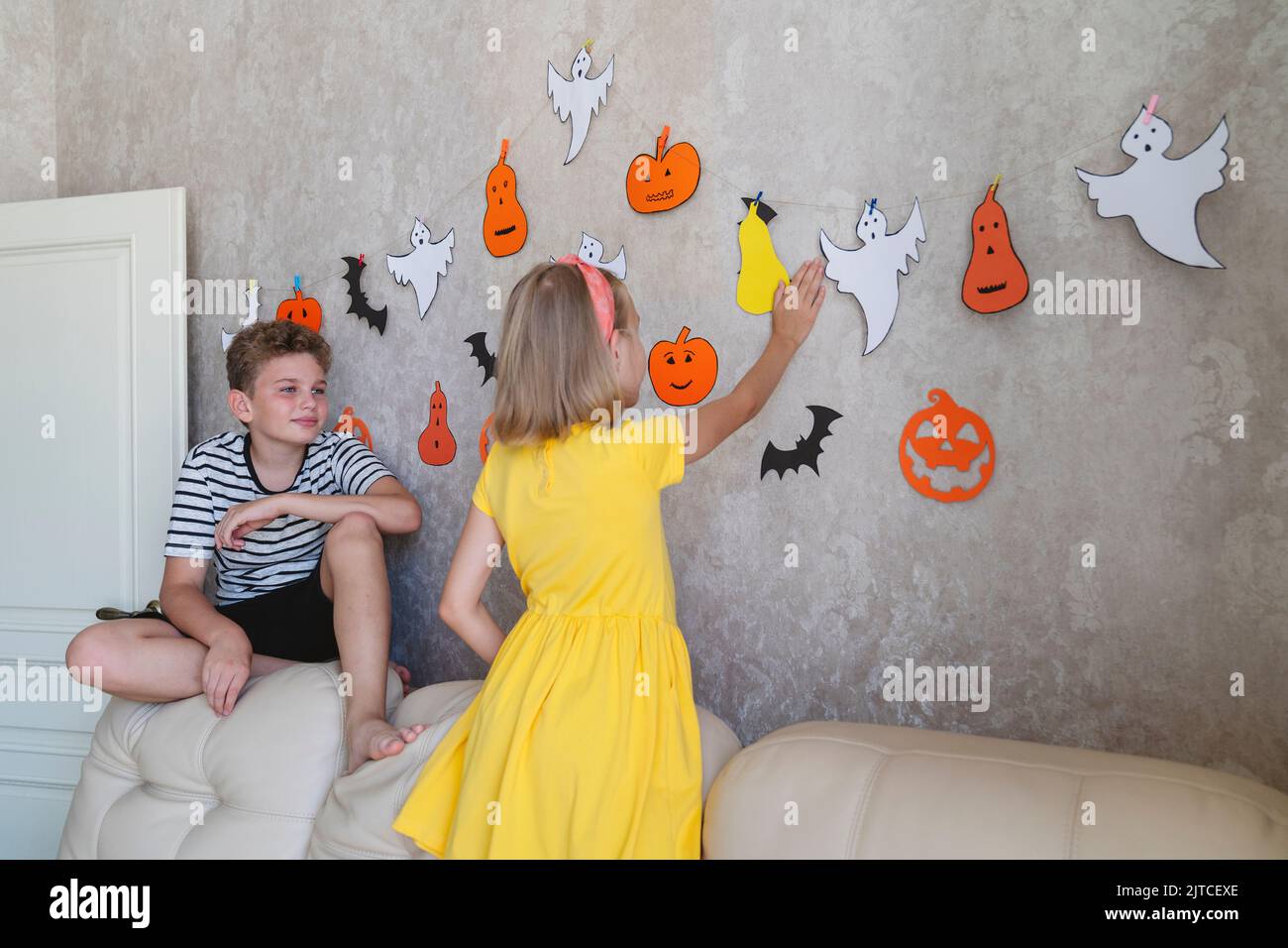 I bambini appendono una ghirlanda per la festa di Halloween sul muro. Foto Stock