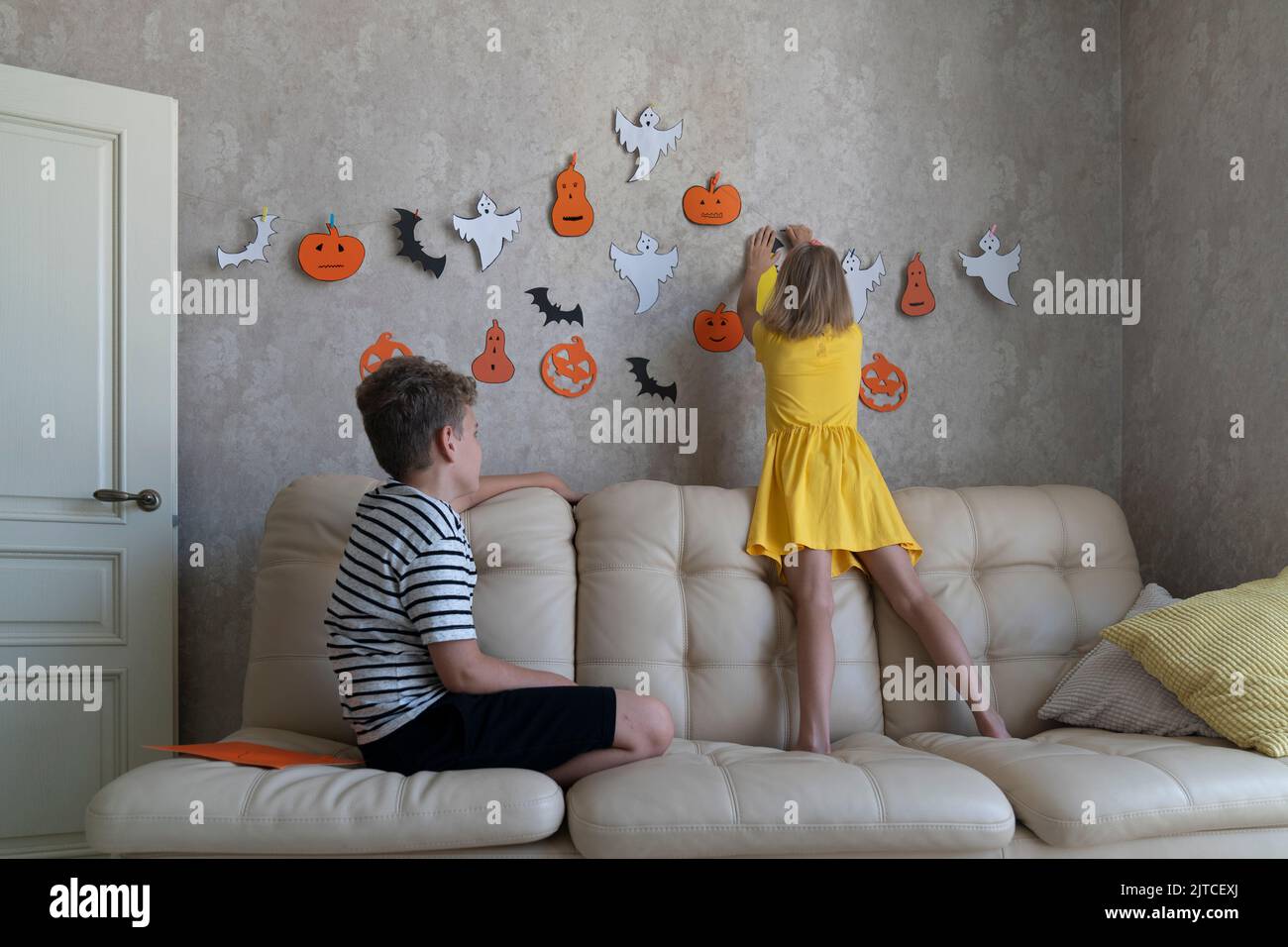 I bambini appendono una ghirlanda per la festa di Halloween sul muro. Foto Stock