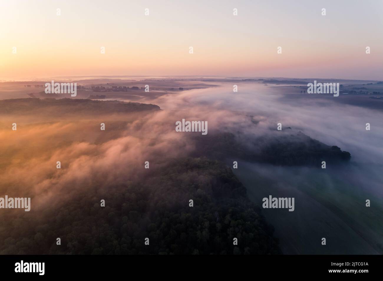 Nebbia fitta che si diffonde su boschi e campi agricoli durante l'alba colorata. Arancione riflesso. Landcape di Roztocze Polonia. Scatto orizzontale. Foto di alta qualità Foto Stock