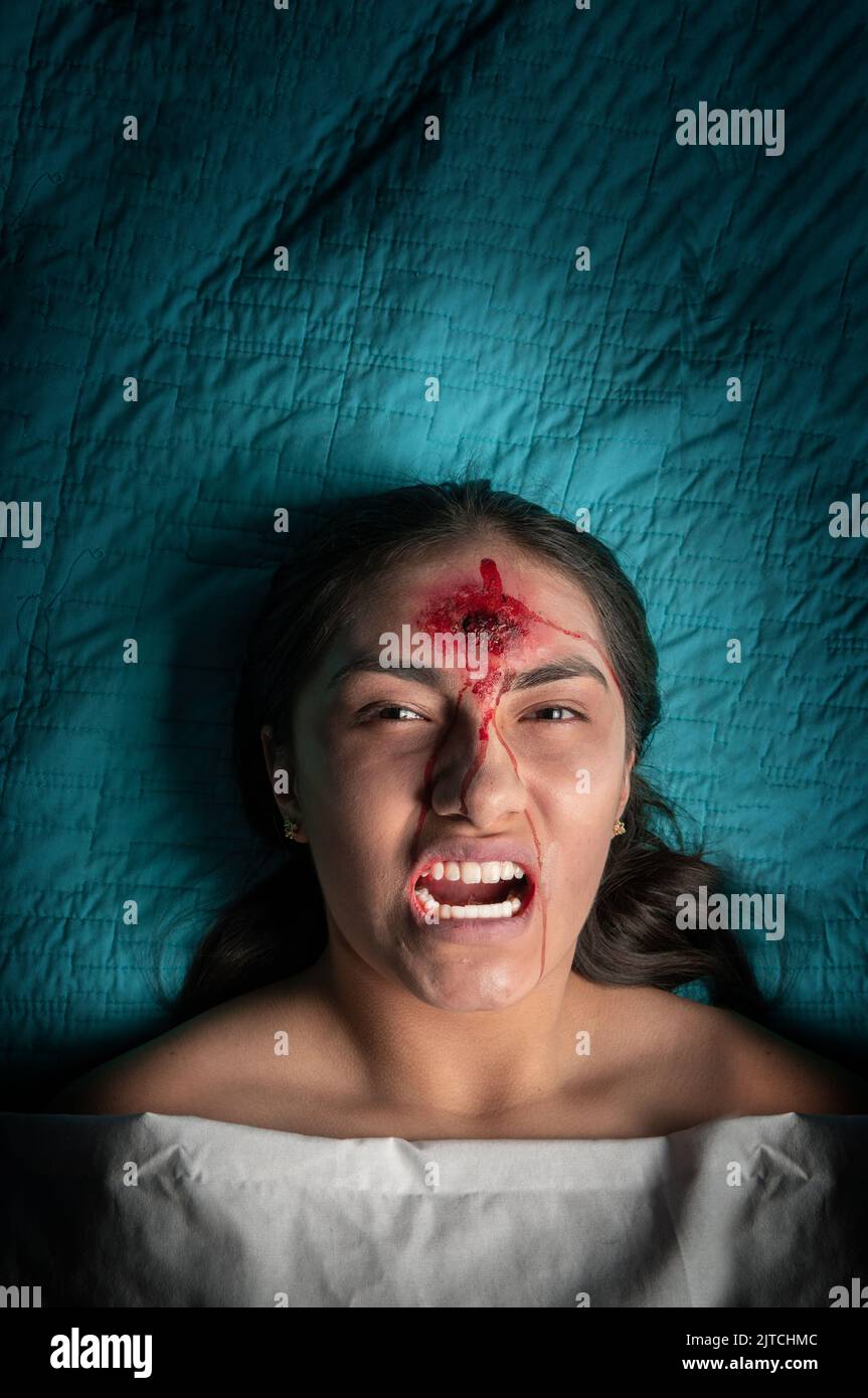 Giovane donna fantasma che guarda la macchina fotografica con un volto minaccioso di terrore e una ferita sulla sua testa. halloween concetto Foto Stock