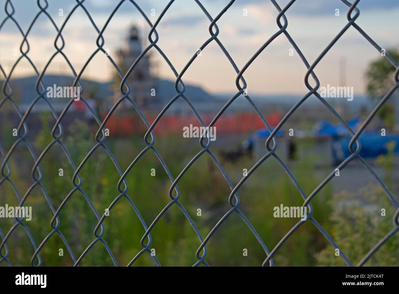 Faro corto, rosso e bianco sul fiume Hudson in fase di restauro e visto attraverso una catena di collegamento recinzione con focus sulla recinzione -12 Foto Stock