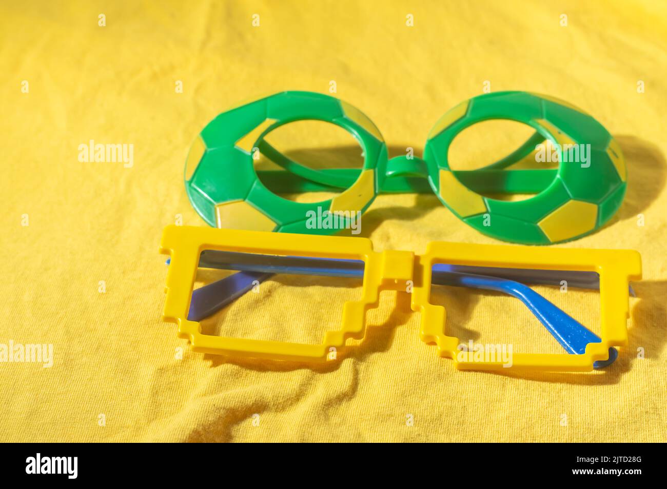 Occhiali con colori brasiliani, giallo e blu verde, concetto di coppa del mondo con sfondo giallo. Foto Stock