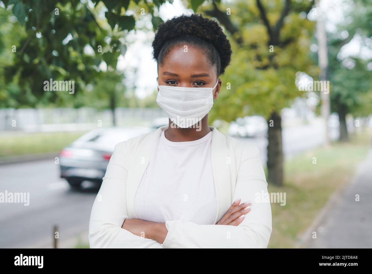 Ritratto di donna che indossa la maschera di sicurezza Covid-19 guardando la fotocamera all'aperto sulla strada. Virus, epidemia, malattia. Nuovo normale in tempi di coronavirus Foto Stock