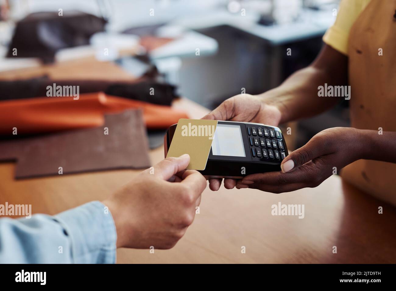 Primo piano di clienti anonimi che pagano con carta di credito oro in un piccolo negozio di affari, tenendo il conto al terminale bancario con schermo bianco mock up, spazio copia Foto Stock