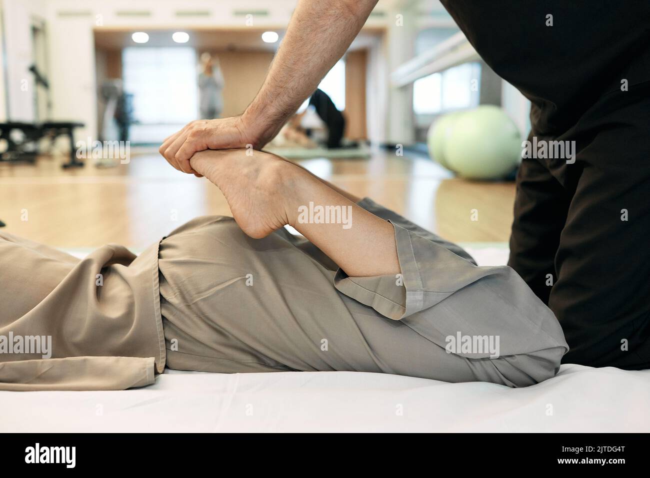 Massaggiatore con tecniche giapponesi Yumeiho premendo sulle gambe piegate del paziente femminile durante il massaggio terapeutico, vista laterale, primo piano. Yumeiho Foto Stock