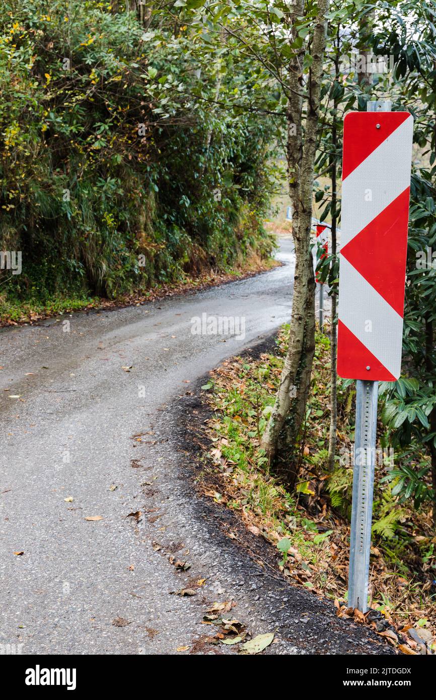 Direzione di svolta, cartello stradale di protezione montato su una strada di una strada di montagna in curva, foto verticale Foto Stock