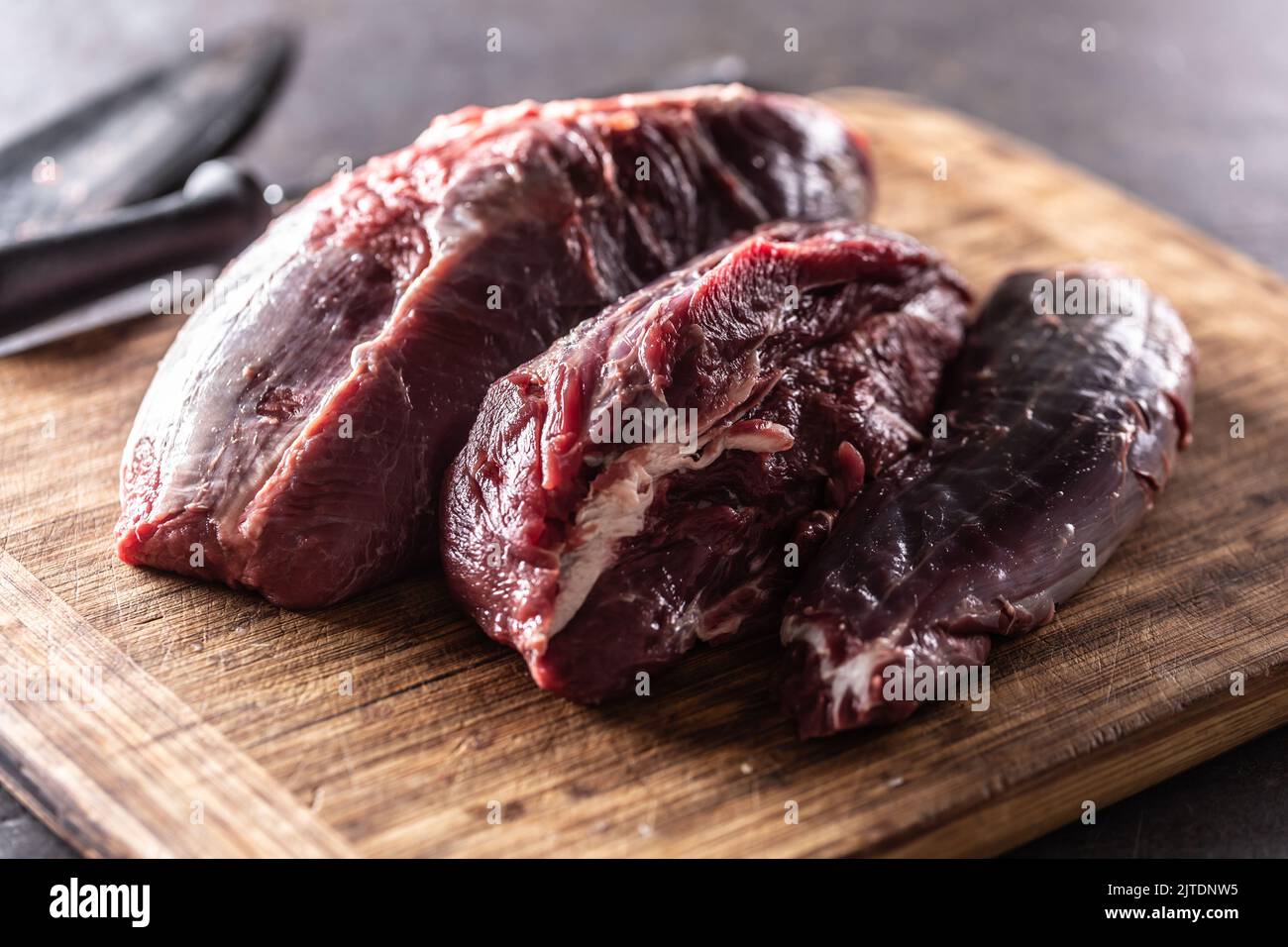 Pezzi di stinco di manzo crudo posti su un tagliere di legno. Foto Stock