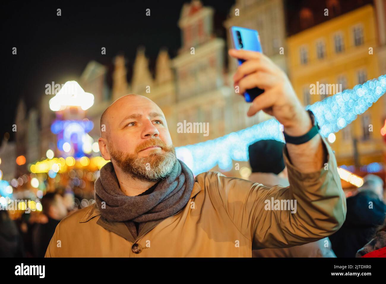 Una persona adulta scatta una foto con il suo smartphone in una fiera di natale della città. L'uomo sta prendendo selfie con lo smartphone Foto Stock