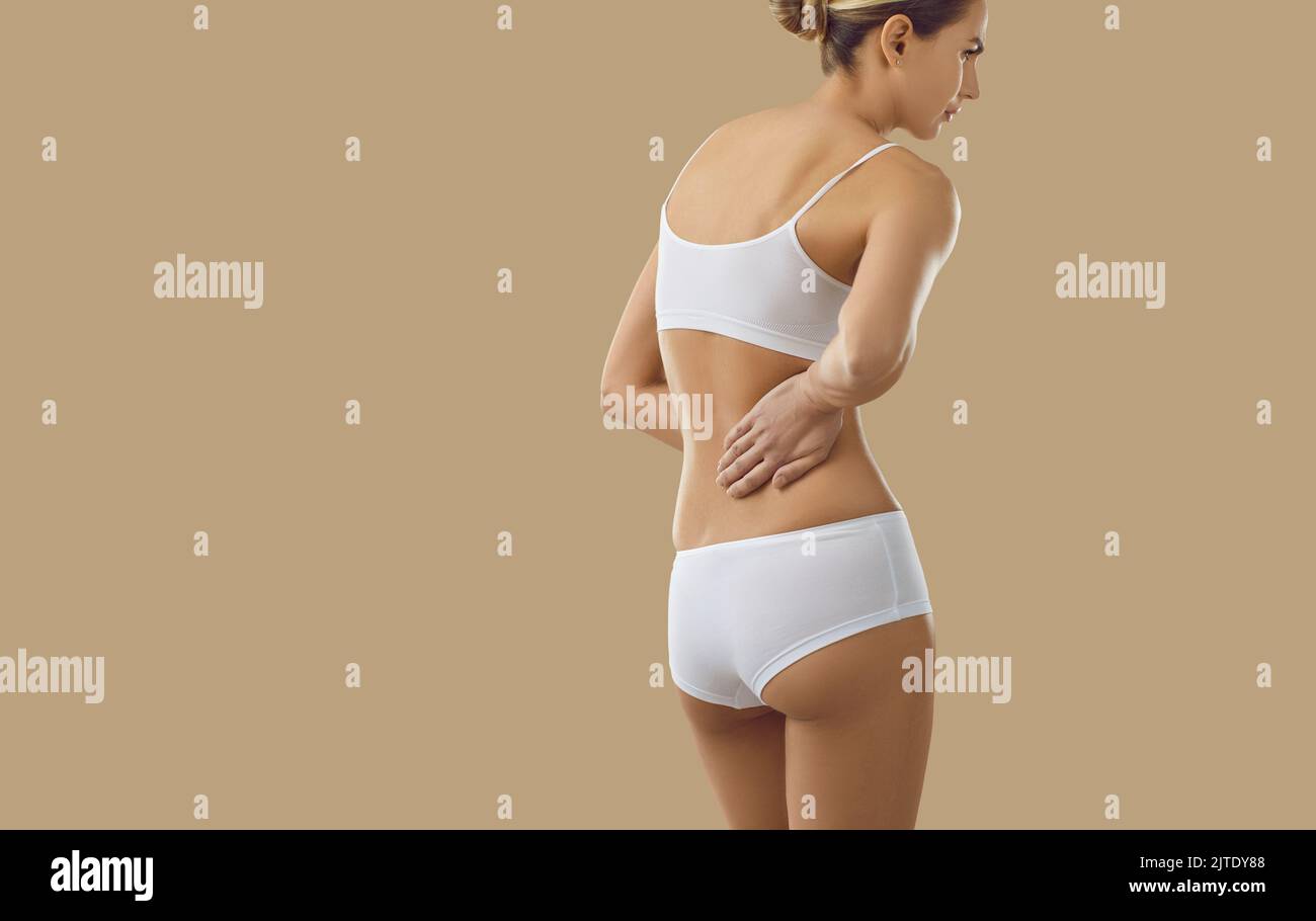 Donna che soffre di mal di schiena a causa di lesioni o malattie renali su sfondo copy space Foto Stock