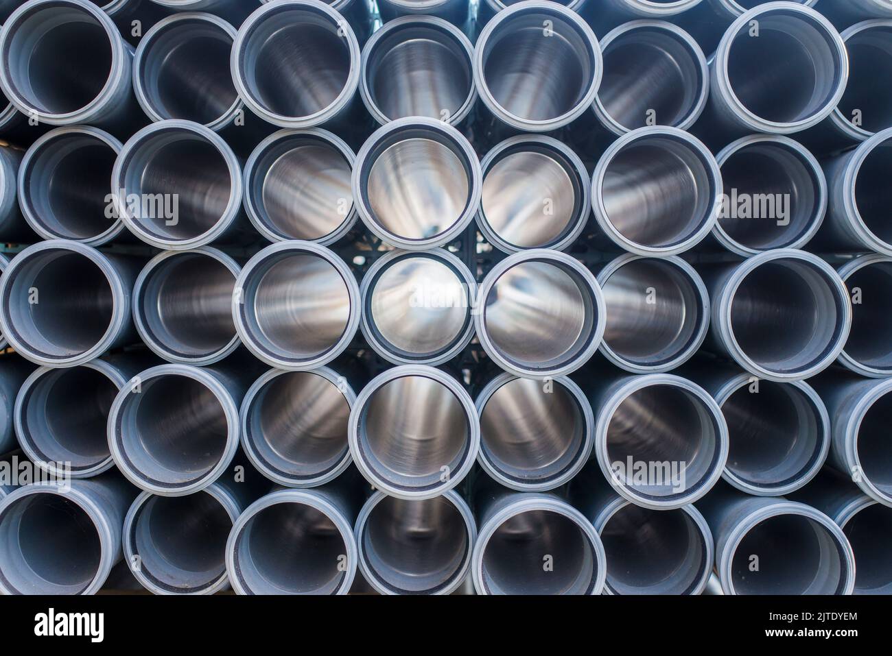 Sfondo di tubi di plastica arancione usati nel cantiere. Struttura e modello del tubo di drenaggio di plastica. Luce attraverso i tubi. Foto Stock