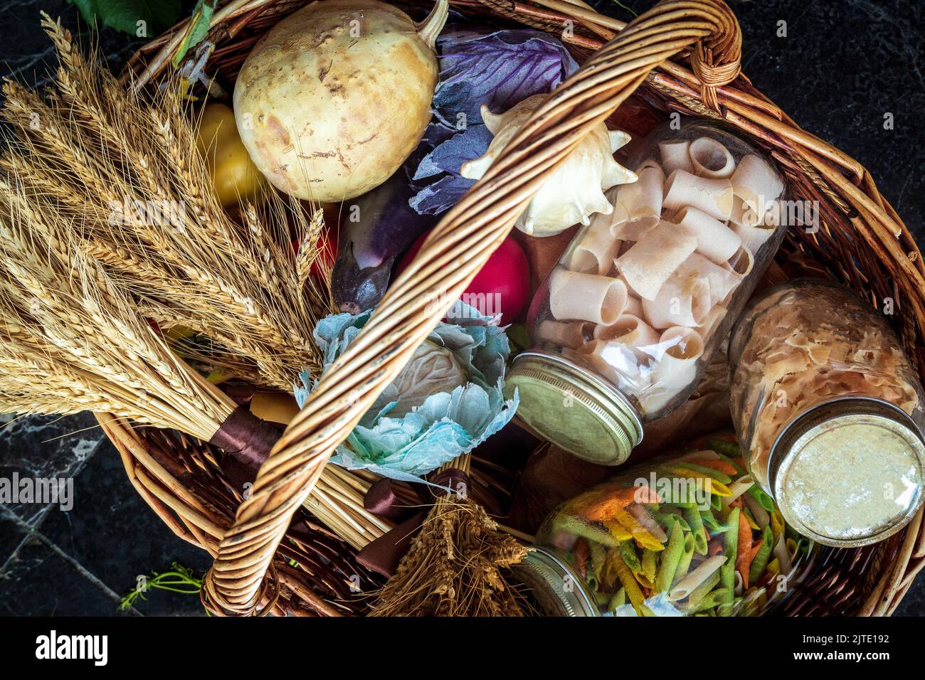 Cestino di vimini con pasta in vasetti di vetro, zucca e un bouquet di grano secco. Set vegetariano dal negozio Foto Stock
