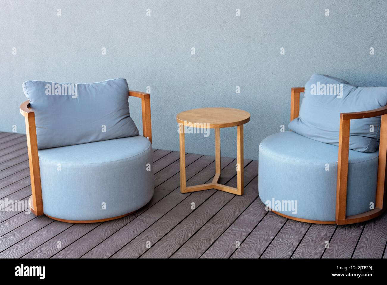 Primo piano di accoglienti sedie tappezzate blu chiaro e un tavolo in legno. Interni moderni. Mobili per una residenza estiva. Messa a fuoco selettiva morbida. Foto Stock