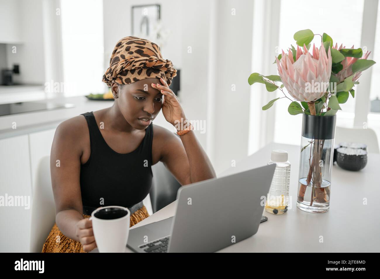 Giovane donna africana nera stanca, esausta dal lavorare studiando duro da casa. Annoiato e frustrato guardando il notebook. Testa appoggiata sulla mano. Sollecitazione Foto Stock