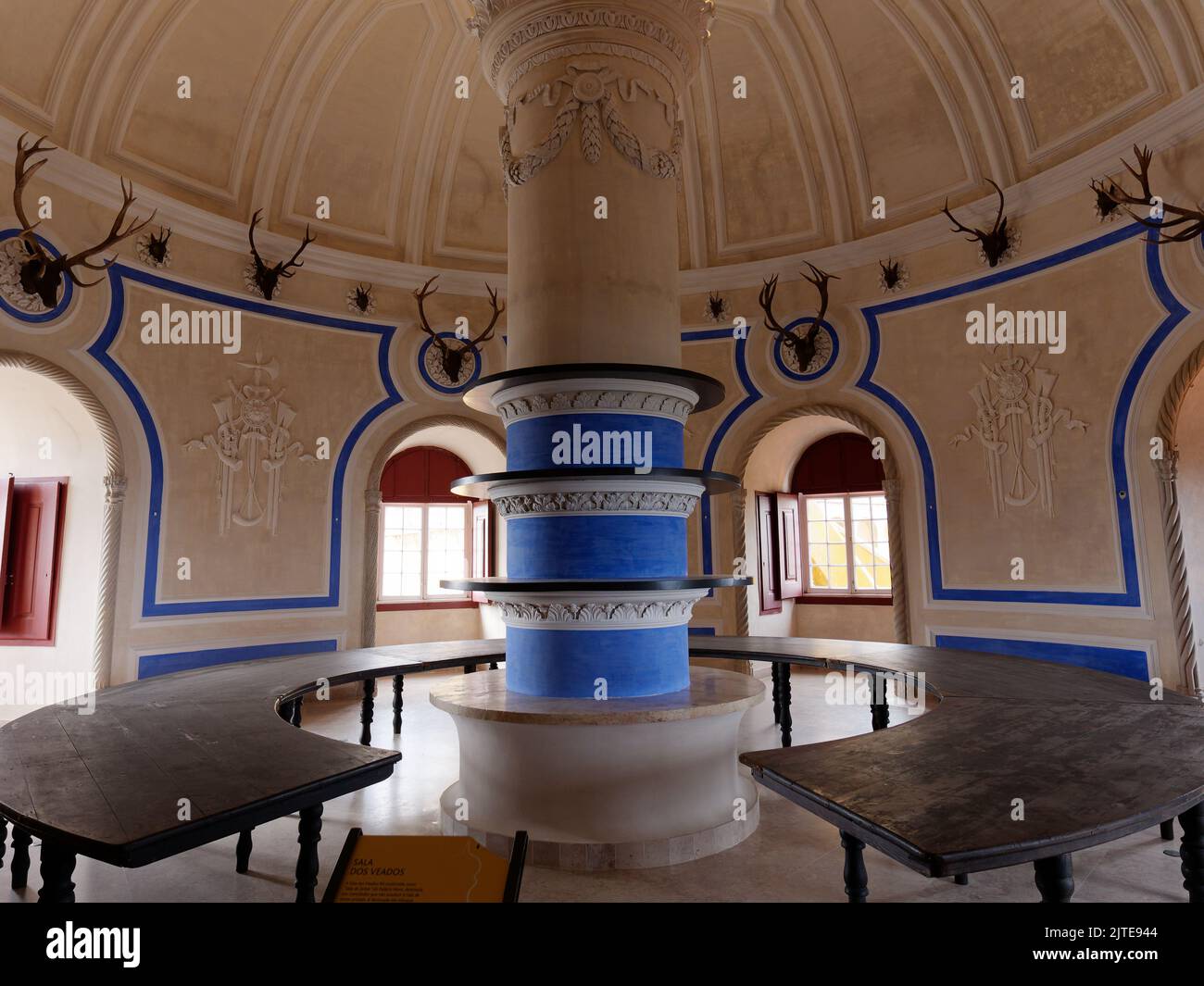 Sala di forma rotonda con panchine rotonde e una colonna centrale all'interno del Palácio da pena, Sintra, quartiere di Lisbona, Portogallo. Le corna sono appese alle pareti Foto Stock