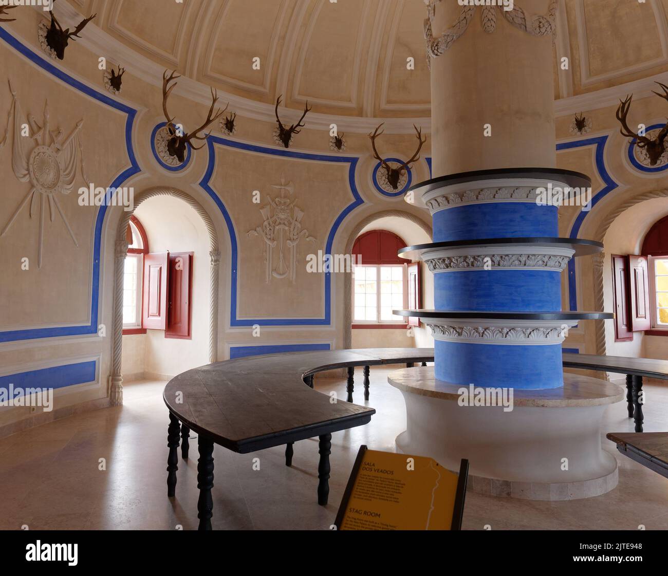 Sala di forma rotonda con panchine rotonde e una colonna centrale all'interno del Palácio da pena, Sintra, quartiere di Lisbona, Portogallo. Le corna sono appese alle pareti Foto Stock
