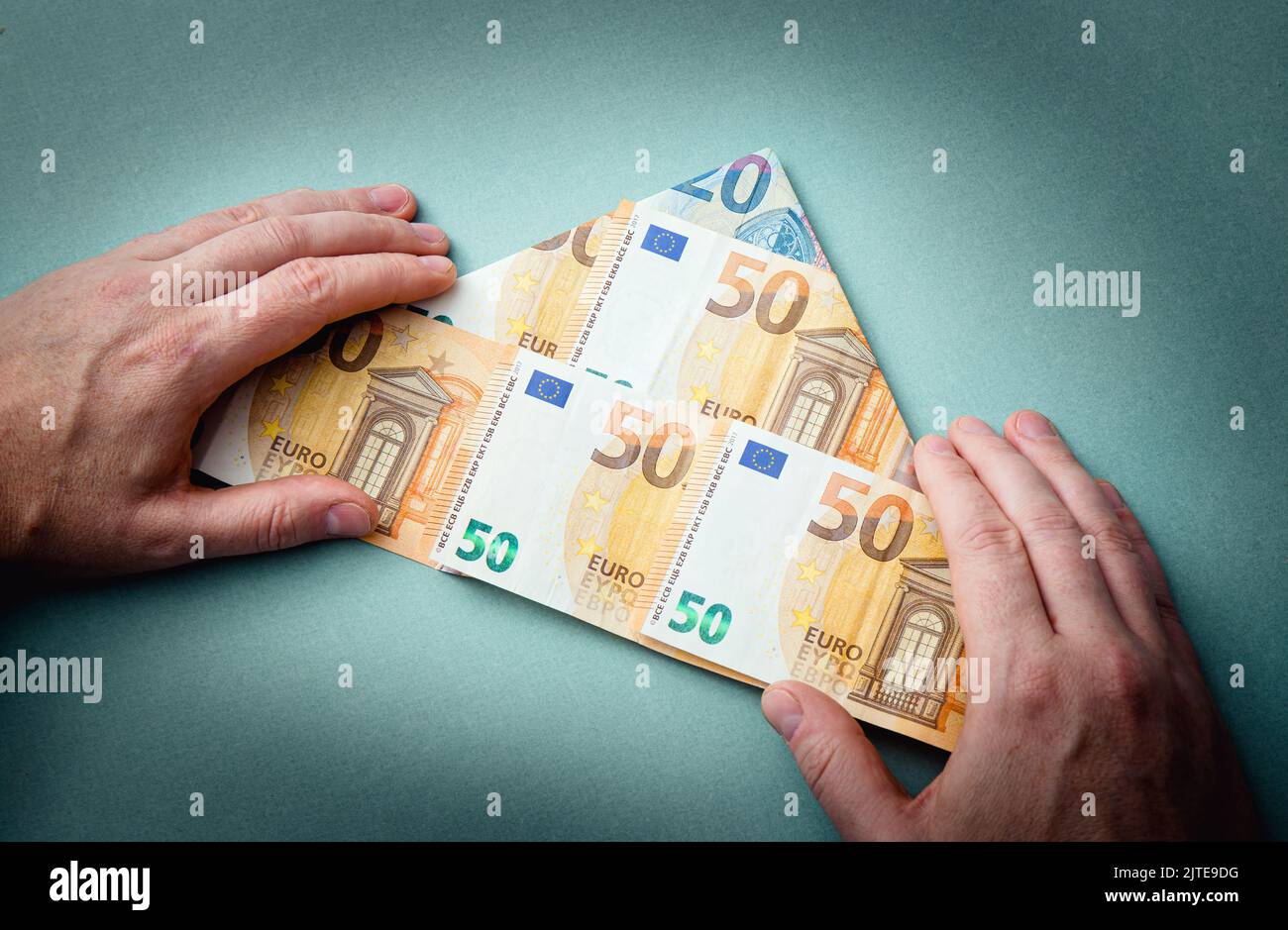 Schema piramidale o concetto di schema Ponzi. Euro denaro piegato a forma di piramide e l'uomo che mostra su sfondo blu, studio shot. Foto Stock