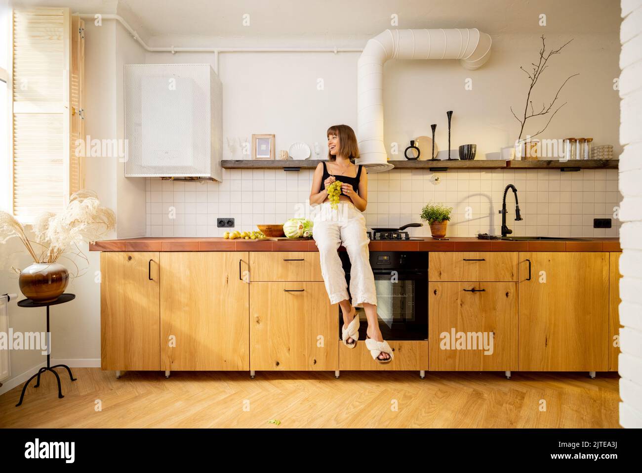 Donna si siede su un tavolo da cucina con cibo sano a casa Foto Stock