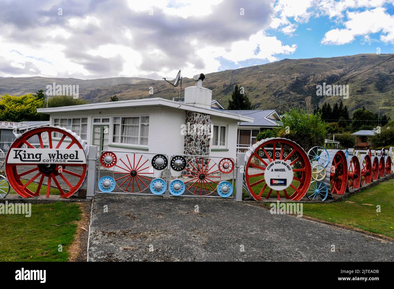 Una casa residenziale / bungalow con il suo recinto giardino di vecchie ruote locomotive a Kingston vicino Queenstown in Otago, una regione sud-orientale di South Isl Foto Stock