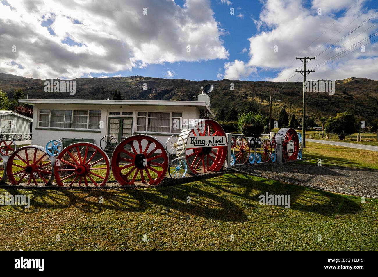 Una casa residenziale / bungalow con il suo recinto giardino di vecchie ruote locomotive a Kingston vicino Queenstown in Otago, una regione sud-orientale di South Isl Foto Stock