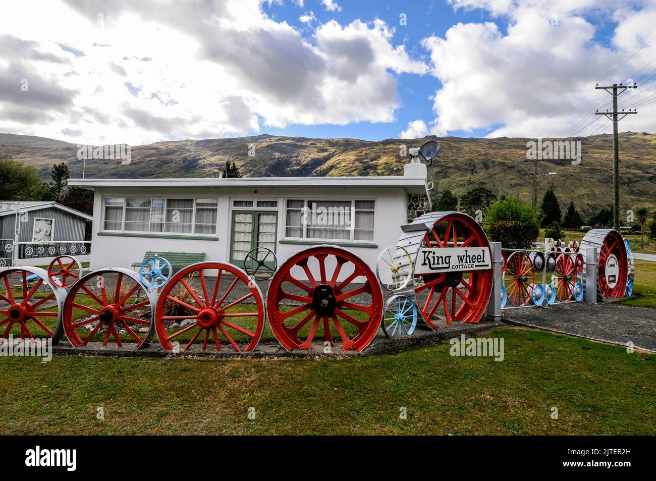 Una casa residenziale / bungalow con il suo recinto giardino di vecchie ruote locomotive a Kingston vicino Queenstown in Otago, una regione sud-orientale di South Isl Foto Stock