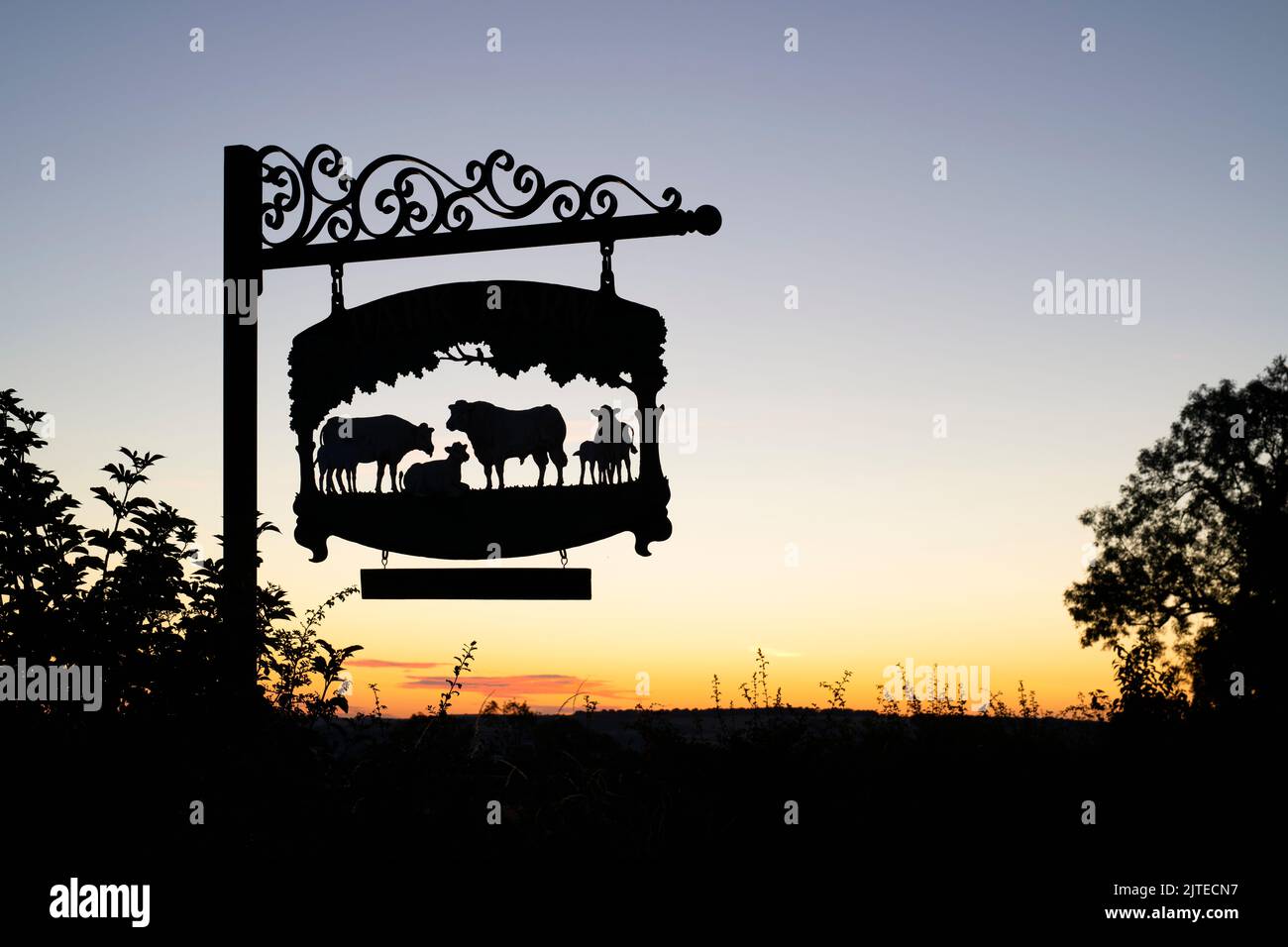 Park Farm segno con Stow on the Wold nella distanza, Cotswolds, Gloucestershire, Inghilterra. Silhouette Foto Stock