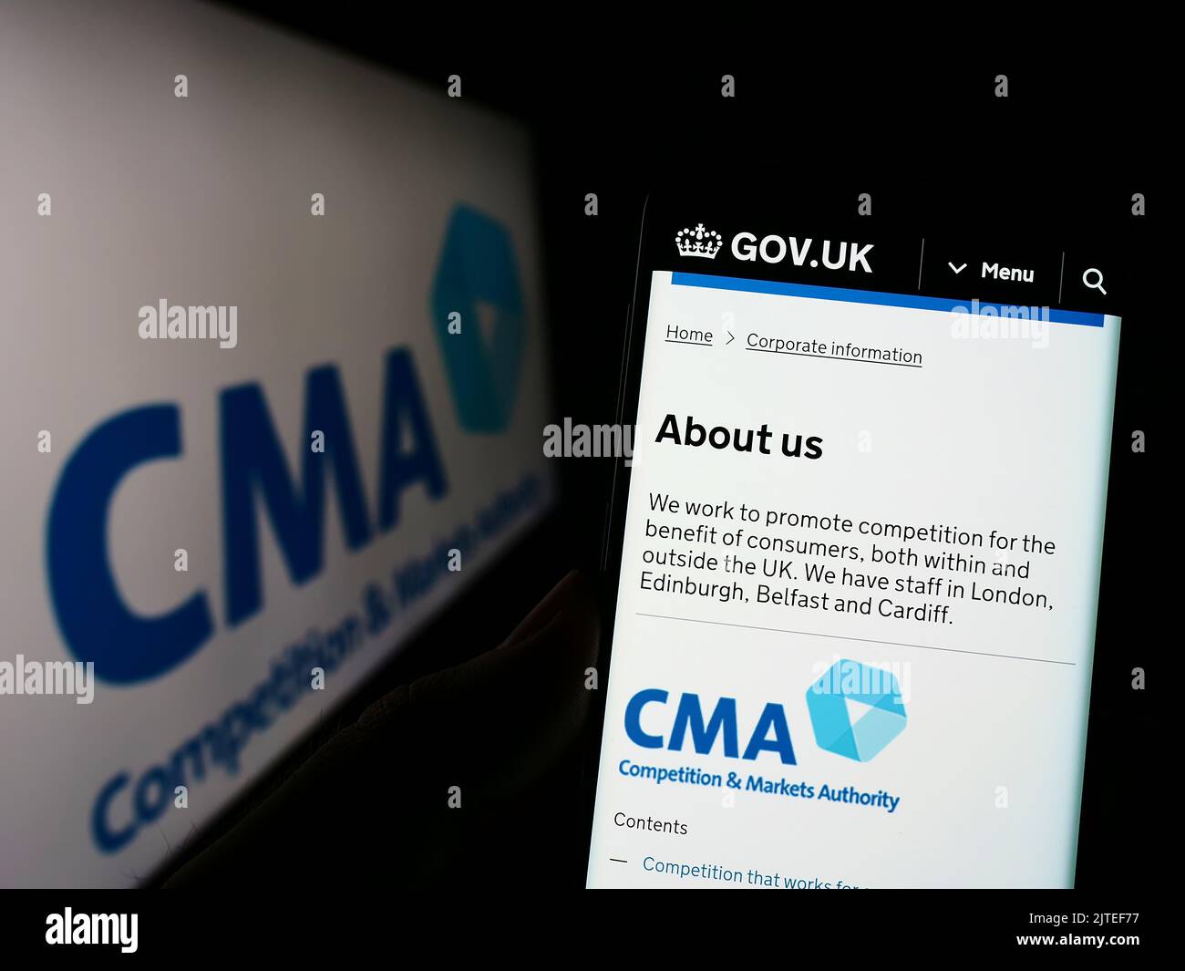 Persona che tiene il cellulare con pagina web della British Competition and Markets Authority (CMA) sullo schermo con il logo. Messa a fuoco al centro del display del telefono. Foto Stock