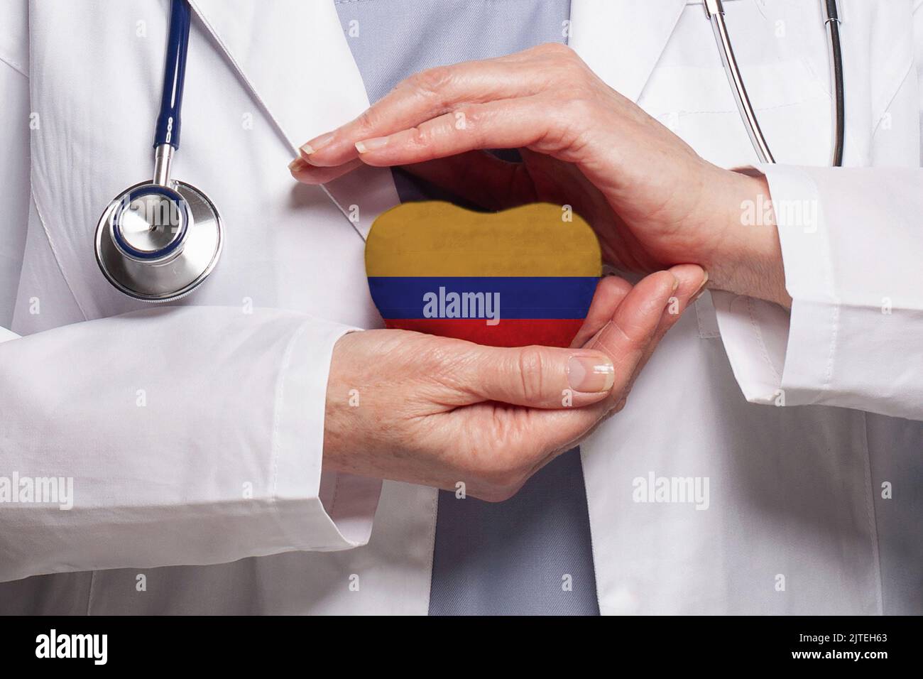 Medico colombiano che tiene il cuore con la bandiera della Repubblica di Colombia sfondo. Concetto di assistenza sanitaria, beneficenza, assicurazione e medicina Foto Stock