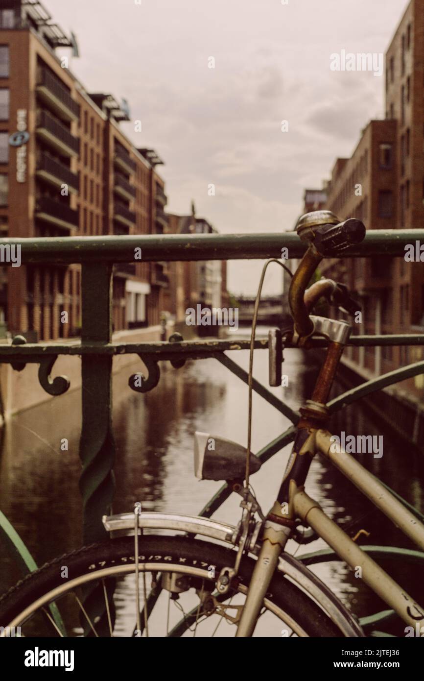 Vecchia bicicletta arrugginente in piedi su una ringhiera a Speicherstadt Amburgo Foto Stock