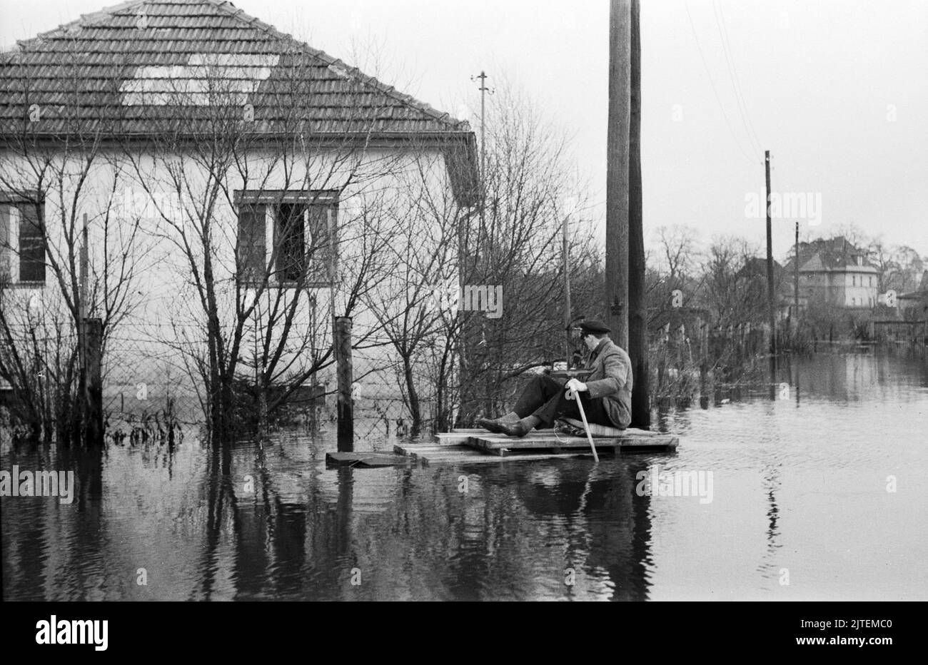 Die Wuhle, ein kleiner Nebenfluss der Spree, bringt Hochwasser nach Kaulsdorf im Bezirk Marzahn-Hellersdorf, hier paddelt ein Mann auf einem notdürftig zusammengeschusterten Floss über die gefluteten Straßen, Berlin, Deutschland 1947. Foto Stock