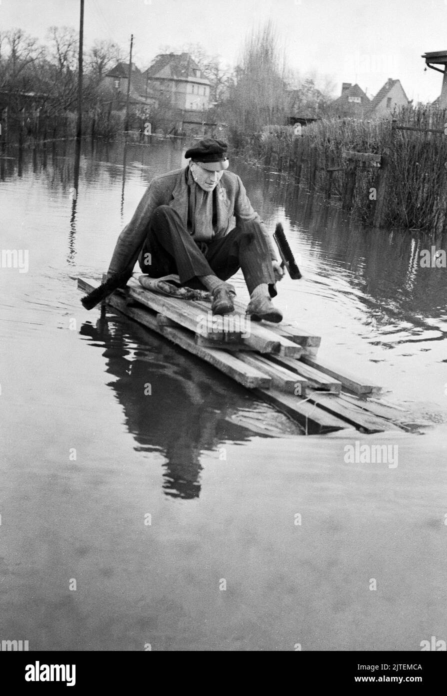 Die Wuhle, ein kleiner Nebenfluss der Spree, bringt Hochwasser nach Kaulsdorf im Bezirk Marzahn-Hellersdorf, hier paddelt ein Mann auf einem notdürftig zusammengeschusterten Floss über die gefluteten Straßen, Berlin, Deutschland 1947. Foto Stock