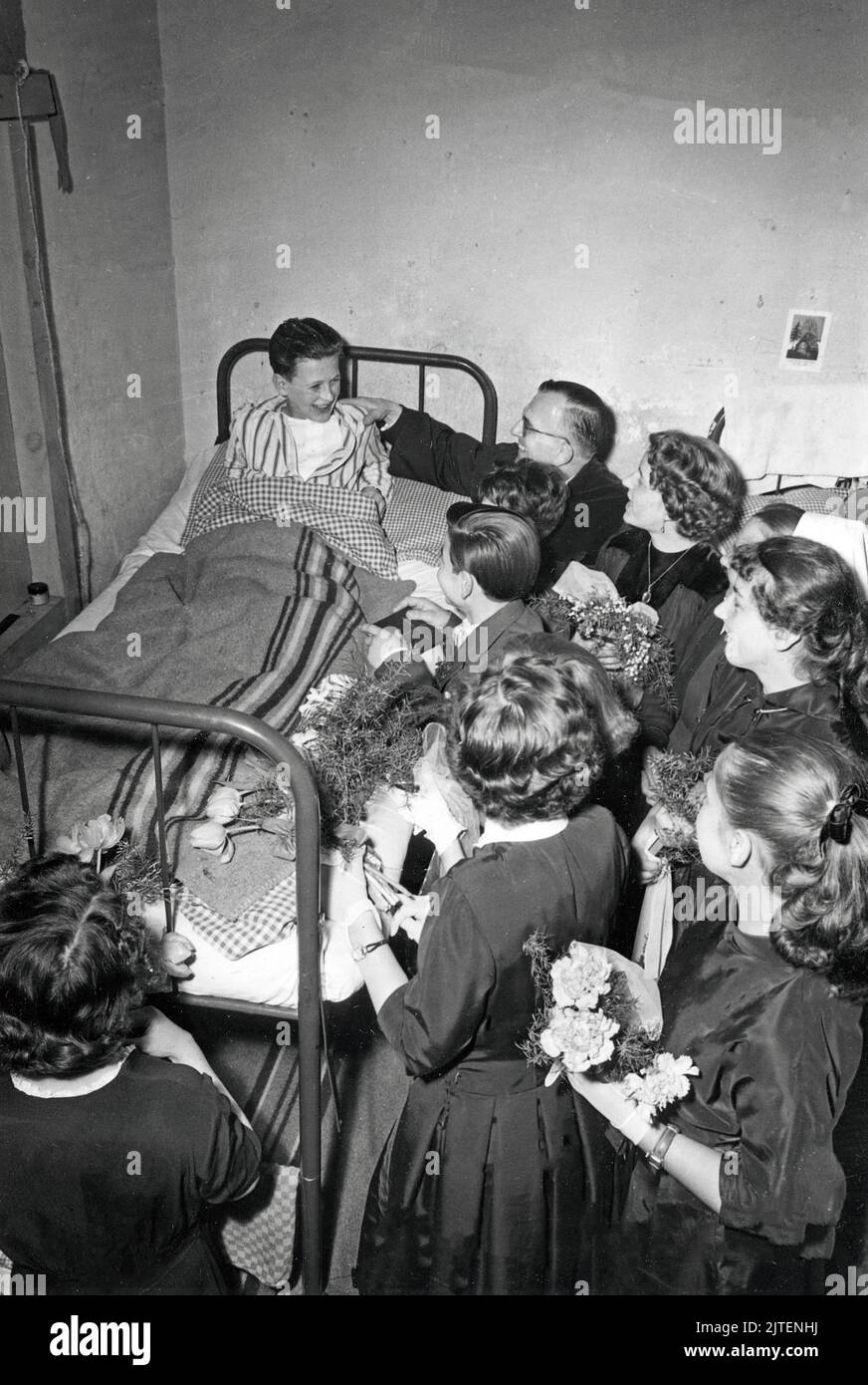 Ein kleiner Flüchtlingsjunge wird beim Aufwachen am Geburtstagsmorgen in der Flüchtlingsunterkunft von den anderen Kindern und Mitbewohnern gefeiert und hochlebengelassen, Berlin, Deutschland 1960. Foto Stock