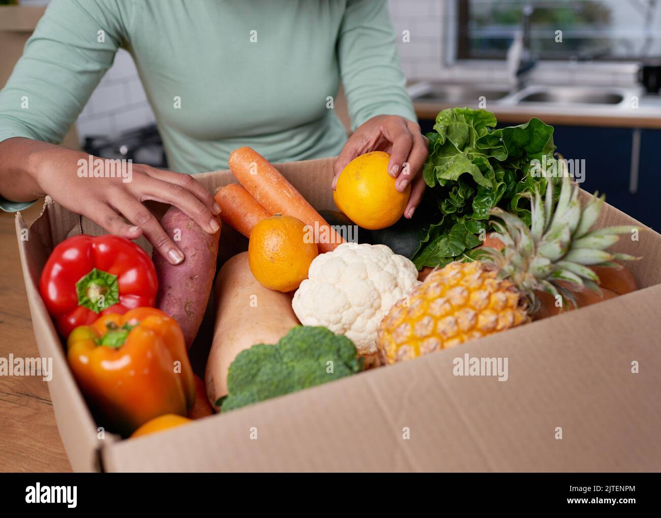 Una giovane donna anonima controlla la sua scatola di consegna di frutta e verdura Foto Stock